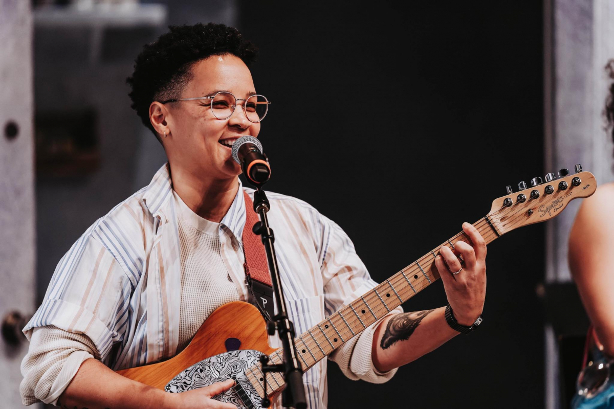 Ottawa-based musician, producer and songwriter Naledi Sunstrum, knowns as OK Naledi with a guitar in front of a microphone.